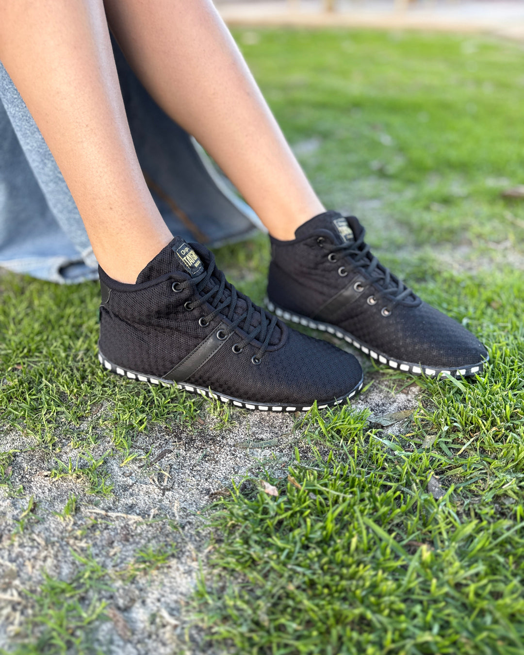 Black high-top Corridalta sneakers on a grassy ground